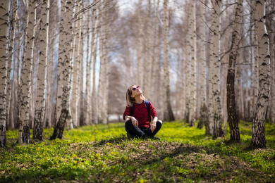 Nainen istuu metsässä