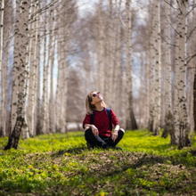 Nainen istuu metsässä